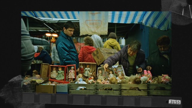 Video Reference: market, stall, dolls, toys, outdoor, people, shopping, flea market, canopy, vendor, browse, toy sale, boxes, crowd, street market, vintage
