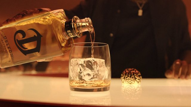 Video Reference: liquor, pouring, whiskey, glass, ice, bar, cocktail, alcohol, drink, bottle, close-up, warm lighting, nightlife, tumbler, bartender