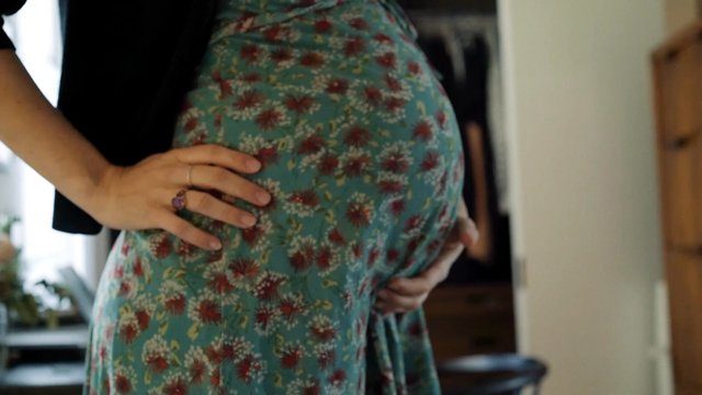 Video Reference: pregnancy, pregnant belly, close-up, torso, hands, floral dress, indoor, home, expecting, motherhood, cropped, lifestyle