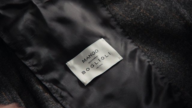 Video Reference: clothing label, fabric, textile, sewn tag, dark fabric, close-up, branding, garment lining, fashion, text