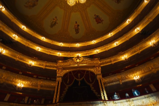 Video Reference: theater, opera house, interior, balcony, ornate, gilded, golden, ceiling, architecture, auditorium, stage, historic, luxury, lighting, decorative, grand