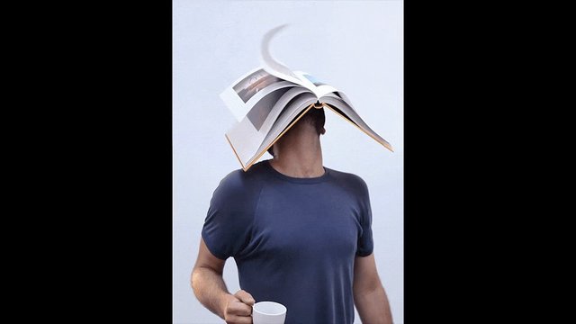 Video Reference: person, book, open book, mug, cup, t-shirt, head covered, playful, indoor, plain background, standing, creative pose