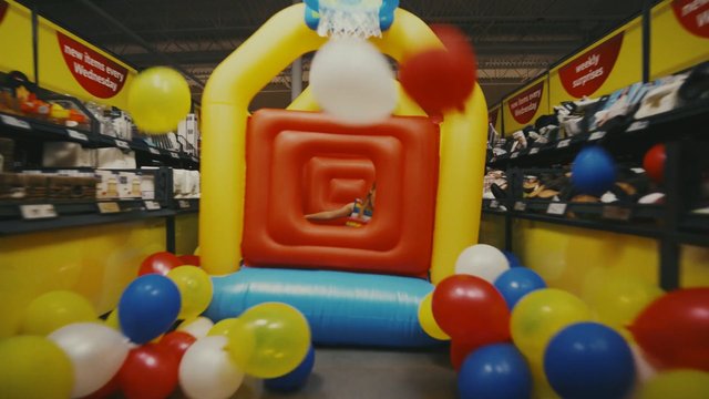 Video Reference: indoor, retail store, aisle, balloons, inflatable, basketball hoop, toy display, colorful, playful, shopping, motion blur, event decor