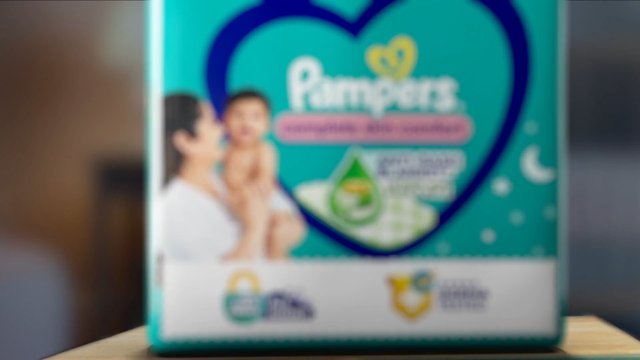 Video Reference: blurry, product box, packaging, parent and baby, heart graphic, teal background, promotional display, indoor, close-up, medicine, baby care, advertisement