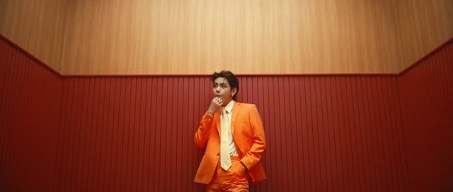 Video Reference: Chin, Orange, Sleeve, Dress shirt, Gesture, Blazer, Public speaking, Audio equipment, Event, Formal wear