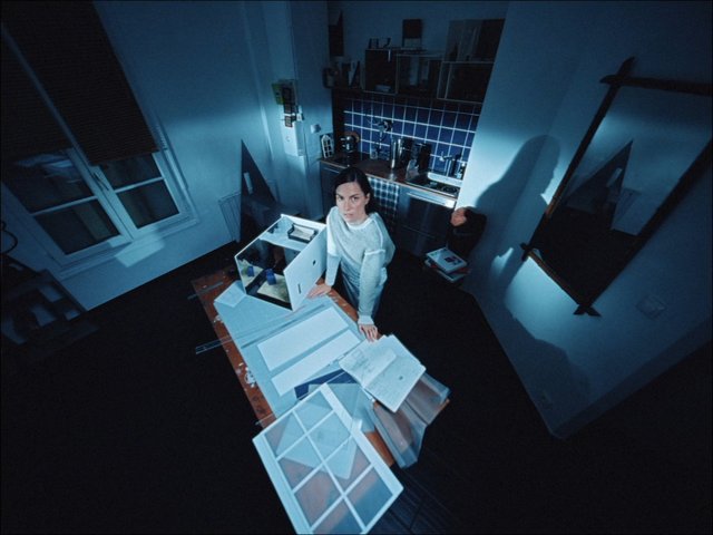 Video Reference: woman, indoor, apartment, kitchen, table, papers, sketches, design, workspace, overhead view, dim lighting, home interior, furniture, standing, window, documents