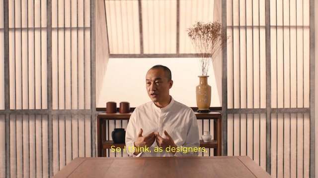 Video Reference: man, interview, indoor, speaking, minimalist interior, wooden table, shelves, vase, decor, subtitle, portrait, office, design, lifestyle, sitting, traditional