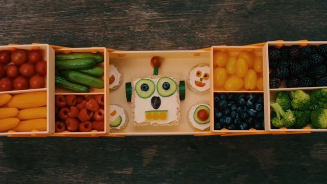 Video Reference: food, fruit, vegetables, top-down, tray, snack, arrangement, colorful, cucumber, berries, broccoli, tomatoes, yellow peppers, creative, lunchbox