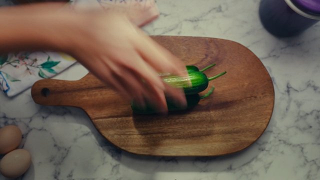 Video Reference: cooking, food prep, hand, cucumbers, cutting board, kitchen, marble countertop, eggs, ingredient, preparation, close-up, home cooking