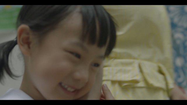 Video Reference: child, smiling, close-up, indoor, portrait, out-of-focus, young girl, family, playful, soft focus