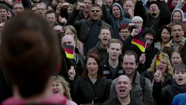 Video Reference: Smile, Shirt, Facial expression, Organ, Human, Coat, Jacket, Fan, Fun, Crowd