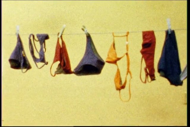 Video Reference: clothesline, hanging clothes, fabric, laundry, indoor, yellow wall, clips, textile, garments, simple background