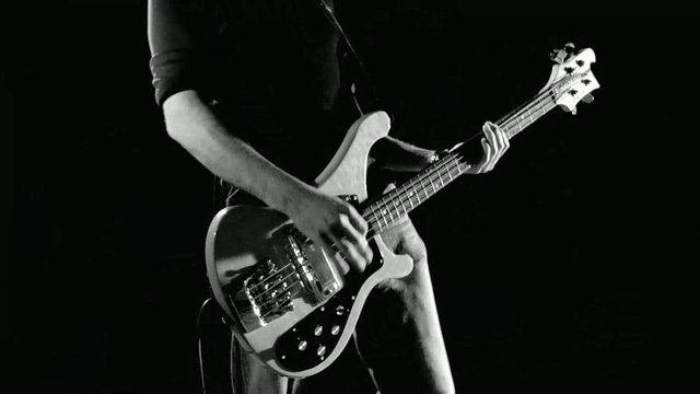 Video Reference: bass guitar, musician, performance, close-up, black and white, live music, instrument, guitarist, hands, stage, concert, string instrument, band, dark background