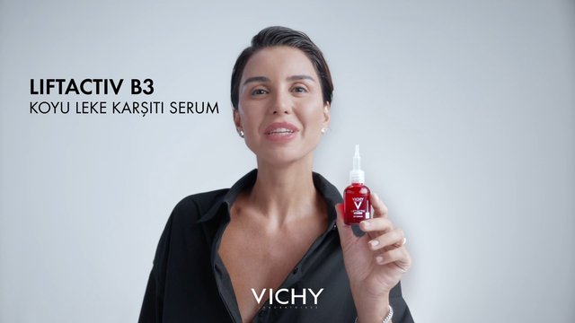 Video Reference: woman, skincare, serum, product shot, cosmetics, beauty, bottle, advertisement, branding, portrait, studio background, anti-spot, Vichy, text overlay, red bottle, handheld product