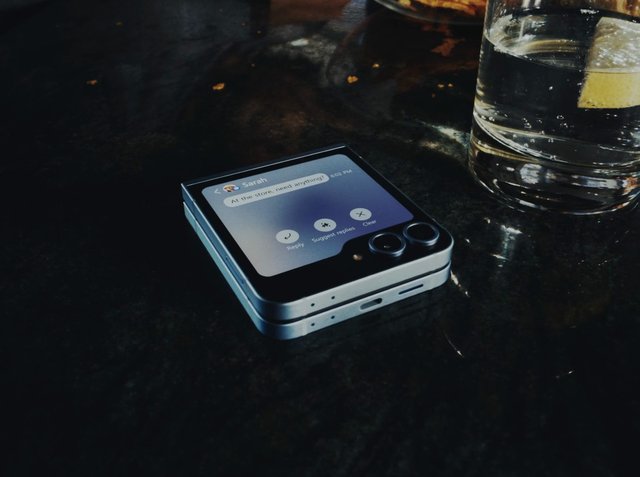 Video Reference: smartphone, foldable phone, message notification, text message, glass of water, lemon slice, table, close-up, technology, mobile device, indoor, screen, conversation, still life