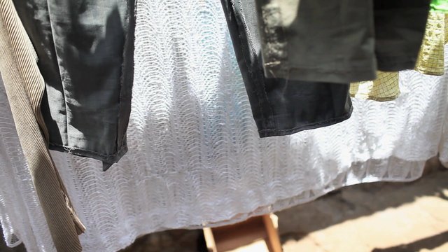Video Reference: laundry, clothesline, hanging clothes, drying, fabric, sunlight, outdoor, textile, clothing, household, white fabric, close-up