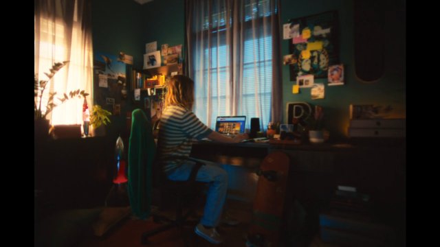 Video Reference: home office, bedroom, person, laptop, desk, window, curtains, indoor, working, skateboard, posters, photos, cozy, natural light, messy room