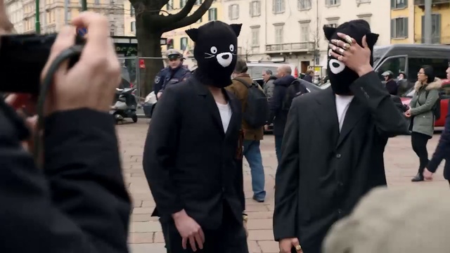 Video Reference: Coat, Gesture, Tire, Street fashion, Suit, Crowd, Formal wear, Event, Eyewear, City