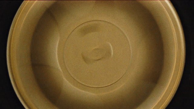 Video Reference: close-up, container, lid, plastic, round, beige, gold, circular, empty, interior, macro, dark background
