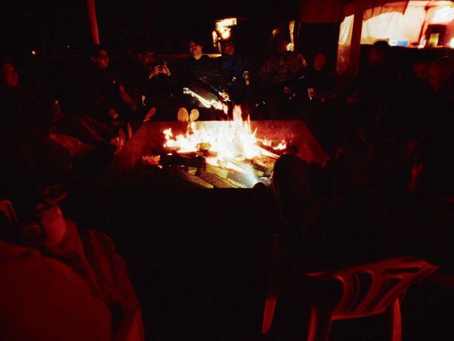 Video Reference: indoor, gathering, people, fire, bonfire, night, dark, warm light, seated, social, group, fireplace, festival, campsite