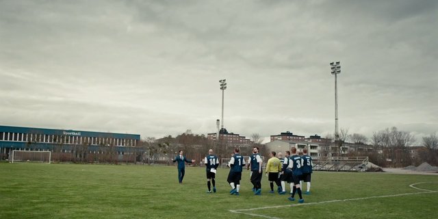 Video Reference: soccer, football field, sports team, outdoor, stadium, players, coach, suit, grass, overcast, goalpost, urban, training, match, uniform