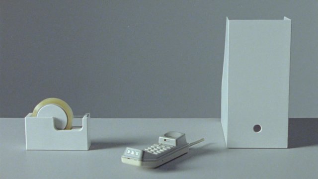 Video Reference: still life, tape dispenser, tape roll, remote control, box, minimalist, gray background, product shot, studio lighting, objects, packaging, simple composition