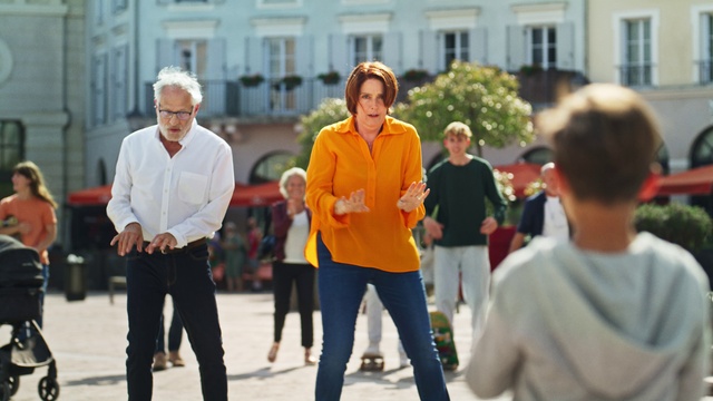 Video Reference: Trousers, Daytime, Orange, Gesture, Public space, Luggage and bags, Leisure, Event, Recreation, Bag