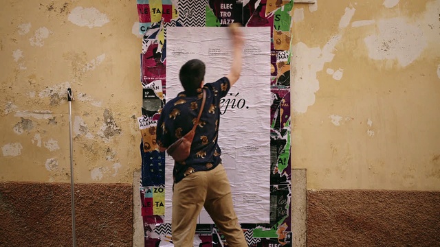 Video Reference: World, Textile, Standing, Font, Street fashion, Public space, Wall, Luggage and bags, Tints and shades, Art