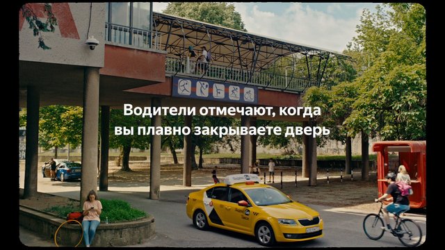 Video Reference: urban, street, taxi, bicycle, pedestrian, cars, outdoors, trees, bridge, raised walkway, parking, daytime, Russian text, city, public space, advertisement