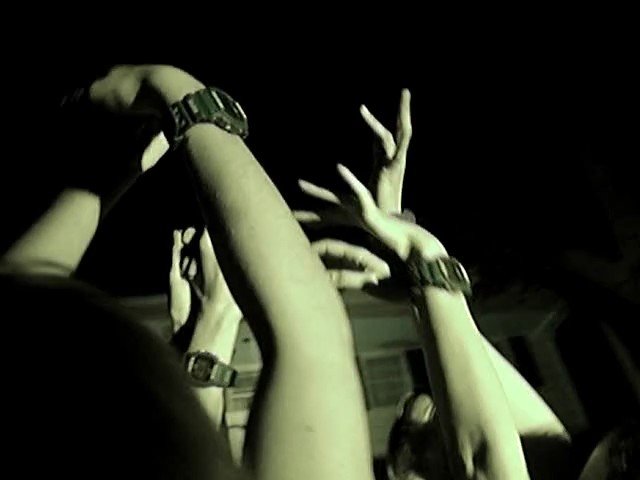 Video Reference: raised hands, arms, crowd, dark scene, green tint, wristwatch, wristband, night, indoor, concert, festival, silhouette, close-up, people, gesture