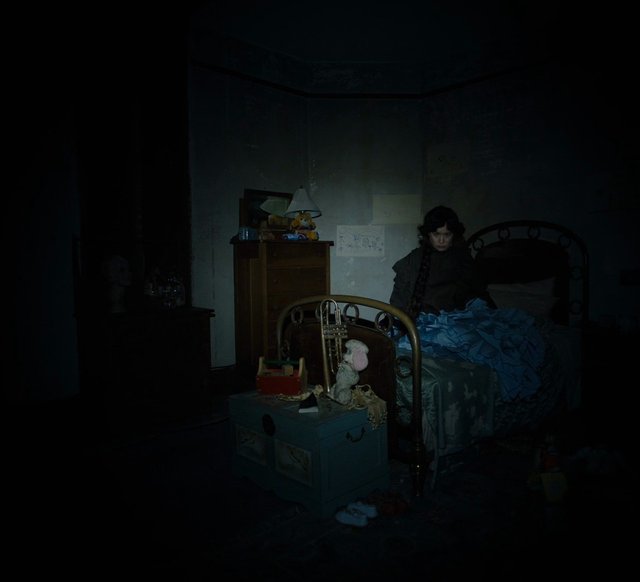 Video Reference: dark interior, bedroom, person, bed, furniture, toy, night, low light, dim room, home interior, doll, dresser, bedroom decor, shadow, moody, indoor