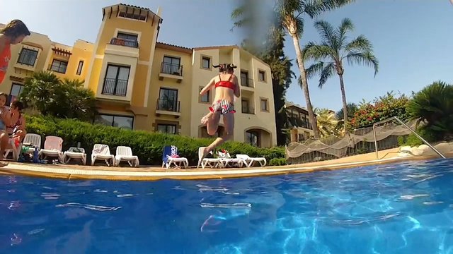 Video Reference: swimming pool, jumping, resort, outdoor, palm trees, summer, vacation, water, people, leisure, hotel, lounge chairs, action, daylight