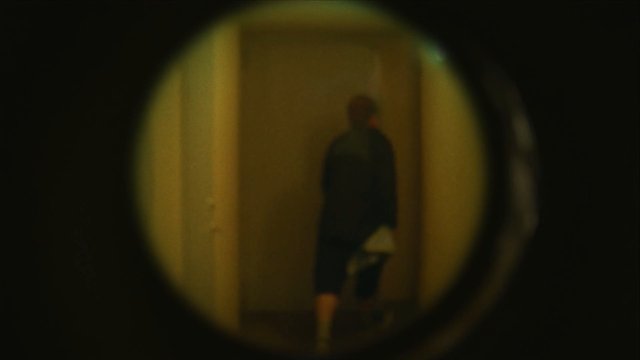 Video Reference: peephole, blurred, person, hallway, doorway, indoor, low light, vignette, silhouette, mystery, security view, dark