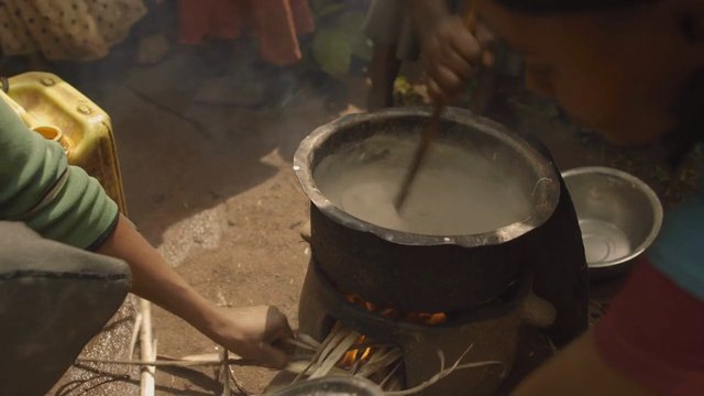 Video Reference: cooking, outdoor, fire, pot, steam, stirring, meal, charcoal, traditional, kitchen, utensils, hands, food preparation
