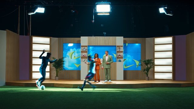 Video Reference: studio, sports, soccer, football, game show, hosts, indoor field, studio set, motion blur, broadcast, television, athletic, lighting, presentation, talk show, entertainment