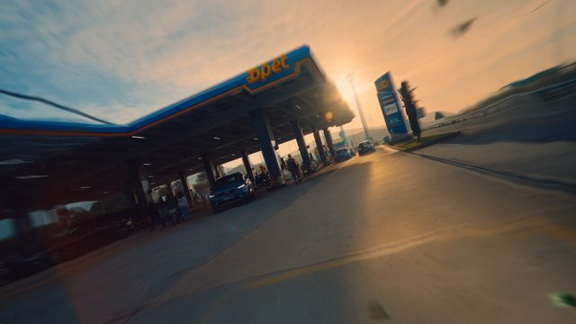 Video Reference: gas station, fuel station, cars, road, sunset, motion blur, urban, pump canopy, traffic, outdoor, travel, evening, service station, roadside