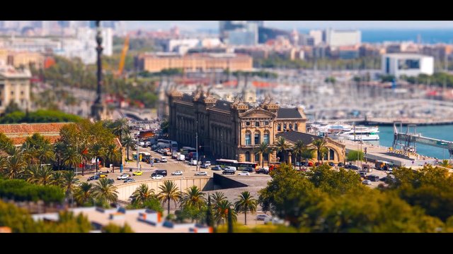 Video Reference: cityscape, coastline, marina, harbor, historic building, palm trees, traffic, road, urban, waterfront, elevated view, tilt-shift, travel, architecture, sea, daylight