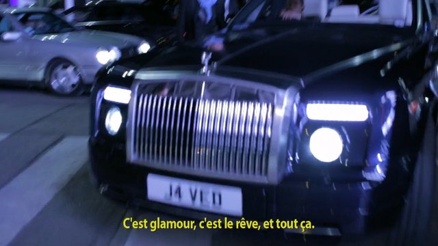 Video Reference: luxury car, night street, headlights, front view, sedan, urban, parked car, chrome grille, dark vehicle, street scene, subtitle, low light