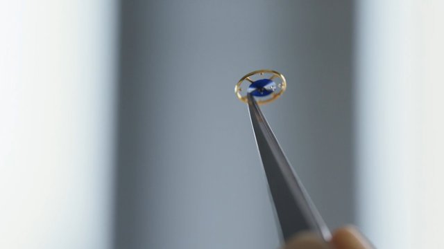 Video Reference: close-up, tweezers, metal object, blue, small object, macro, handheld, precision tool, abstract, blurred background, indoors, minimalist