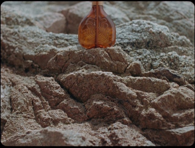 Video Reference: bottle, glass, rock, stone, outdoors, close-up, texture, brown, surface, nature