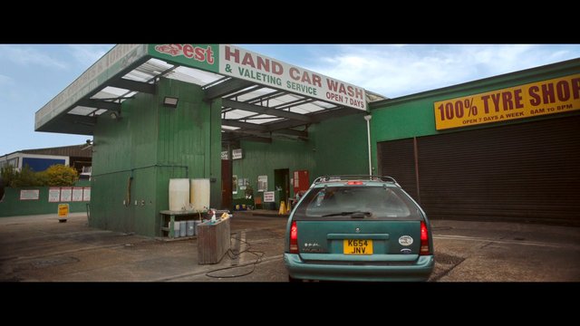 Video Reference: car wash, tyre shop, auto service, station wagon, parked car, exterior, commercial building, garage, vehicle, urban, daytime, signage