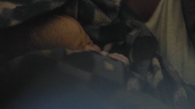 Video Reference: dim, blurry, close-up, person, blanket, indoor, sleeping, low-light, soft focus, partial view