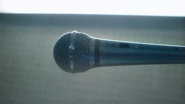 Video Reference: microphone, close-up, audio, handheld, music, speech, podium, metal grille, indoor, blurred background
