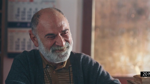 Video Reference: Forehead, Beard, Smile, Facial hair, Wrinkle, Moustache, Event, Wood, Dress shirt, Sitting