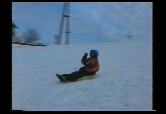 Video Reference: snow, winter, ski slope, person, helmet, orange jacket, sliding, snowy hill, outdoor, ski resort, action, cold, sports