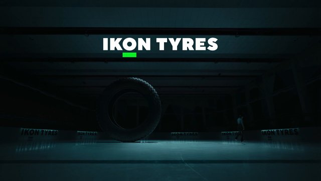 Video Reference: indoor, stage, showroom, tire, tyre, branding, logo, dark, spotlight, display, sculpture, person, minimal, presentation