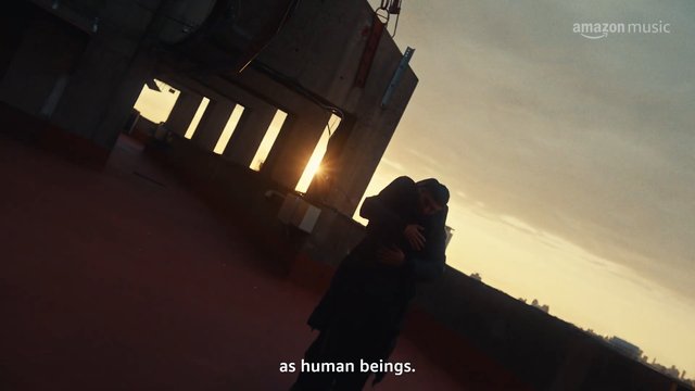 Video Reference: rooftop, sunset, silhouette, person, urban, industrial, skyline, evening, backlit, outdoor, subtitles, Amazon Music, standing, cityscape, dramatic lighting