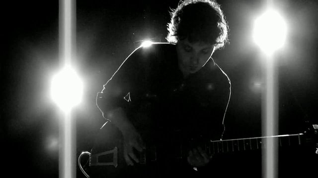 Video Reference: guitar, musician, silhouette, backlit, stage, concert, electric guitar, performance, dark background, spotlights, live music, artist, instrument, dramatic lighting