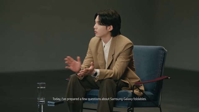 Video Reference: Suit trousers, Chair, Collar, Blazer, Suit, Formal wear, Event, Spokesperson, Audio equipment, Public speaking