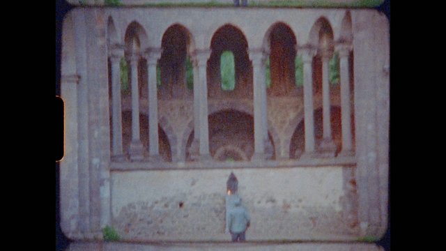 Video Reference: archway, stone building, historic architecture, courtyard, person, small figure, blurred, low resolution, old film, facade, arches, outdoors